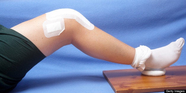 Closeup of total knee replacement patient exercising using 'doughnut' on wooden board.