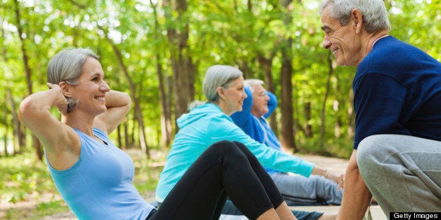 Senior fitness instructor assisting student during outdoor exercise class