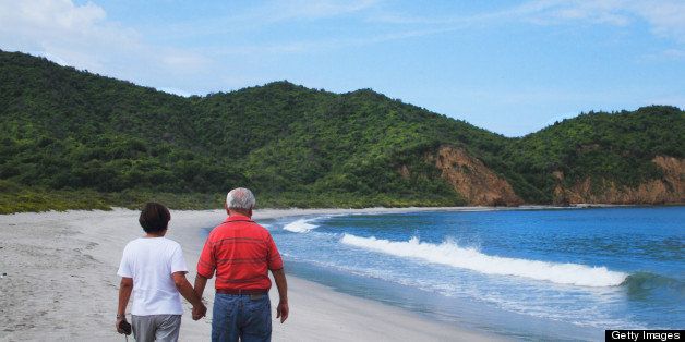 Mature Hispanic couple walking on Pacific Ocean beach in Ecuador