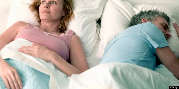 Woman awake in bed beside husband