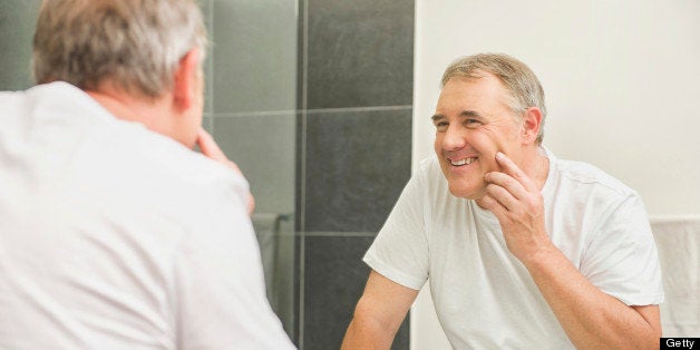 Older man examining himself in mirror