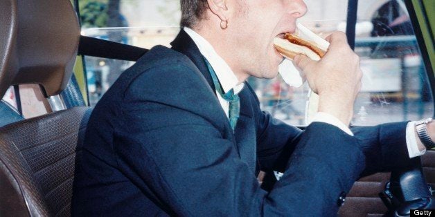 A man eating sausage in a car.