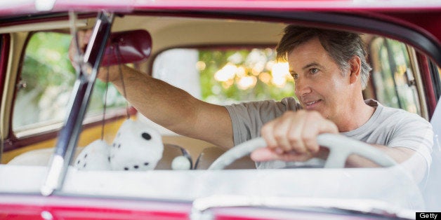 Senior man adjusting rear-view mirror in vintage car