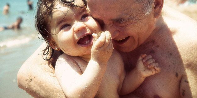 Grandfather hugging her granddaughter on beach