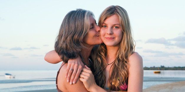 Mother and daughter (14-15) hugging on beach