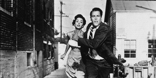 Becky Driscoll (German-born actress Dana Wynter) and Dr. Miles Bennell (American actor Kevin McCarthy) hold hands and run from unseen terror in a film still from the horror motion picture 'Invasion of the Body Snatchers,' directed by Don Siegel, 1956. The film concerns tells the story of a doctor who returns to his small town home to discover that some of his neighbors seem to have been replaced by alien duplicates. (Photo by Allied Artists/Getty Images)