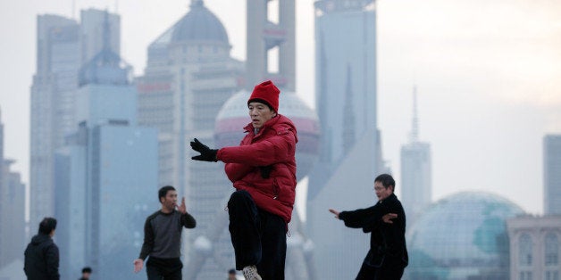 People practice Tai Chi on the Bund as commercial buildings stand in the Pudong area, background, in Shanghai, China, on Tues