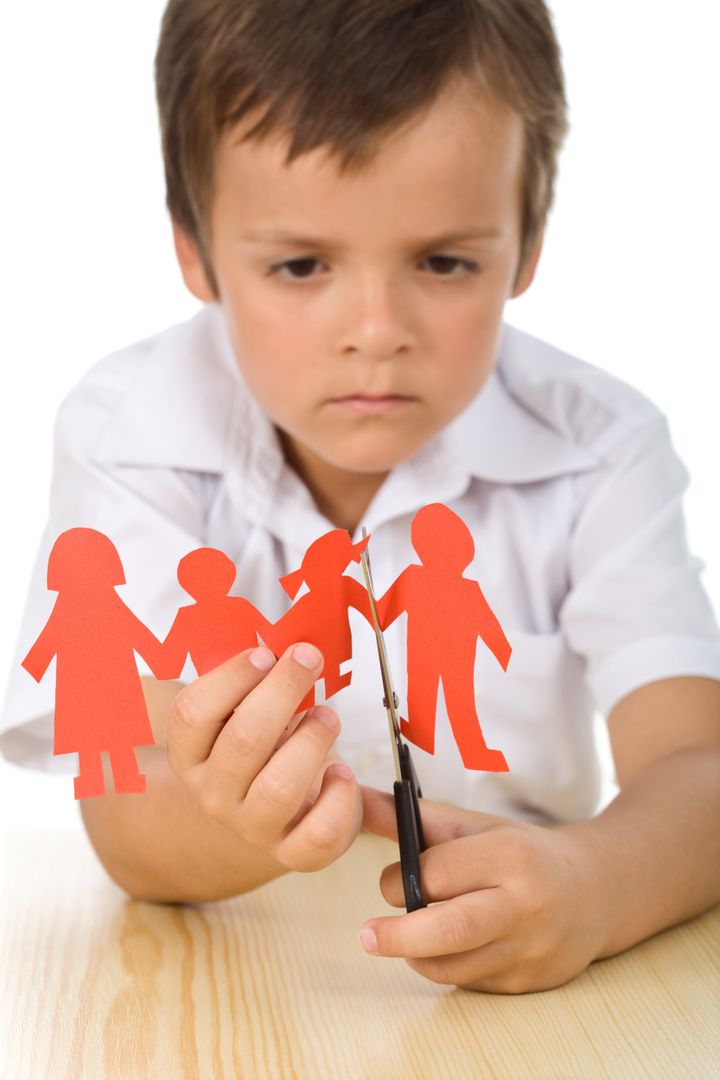Sad boy cutting paper people family - divorce effect on kids concept, isolated closeup
