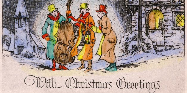 Greeting card shows an illustration of two musicians and a man whol holds a lantern as they perform outdoors in the snow, accompanied by the text, 'With Christmas Greetings,' early twentieth century. (Photo by Transcendental Graphics/Getty Images)