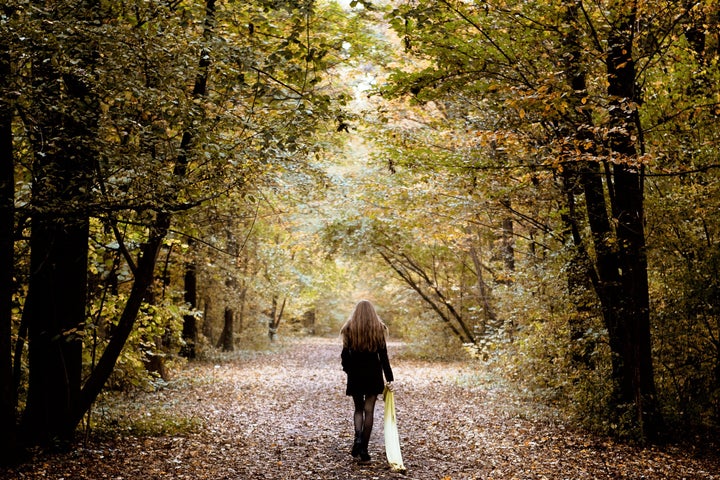 Sad lonely woman walking alone into the woods