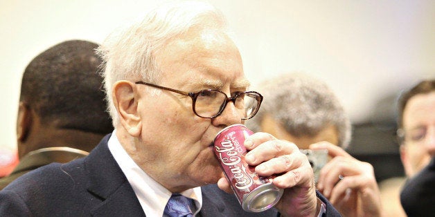 Warren Buffett, chief executive officer of Berkshire Hathaway, drinks a Cherry Coca-Cola as he tours the exhibition floor pri