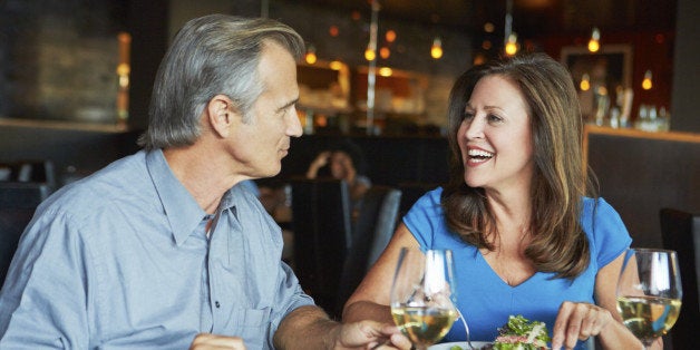 Mature Couple Enjoying Meal At Outdoor Restaurant With Glass Of Wine