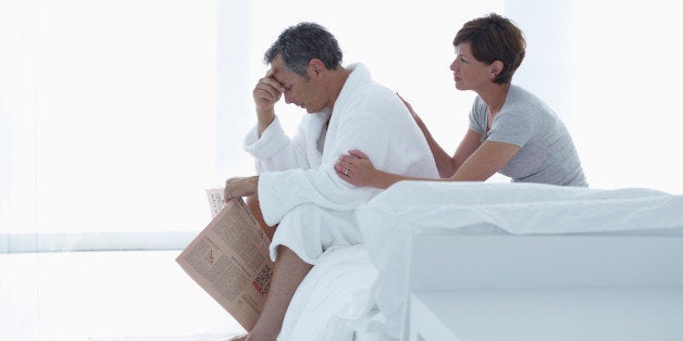 Upset Man Holding Newspaper, Sitting on Bed