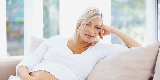 Thoughtful mature pregnant woman relaxing on couch
