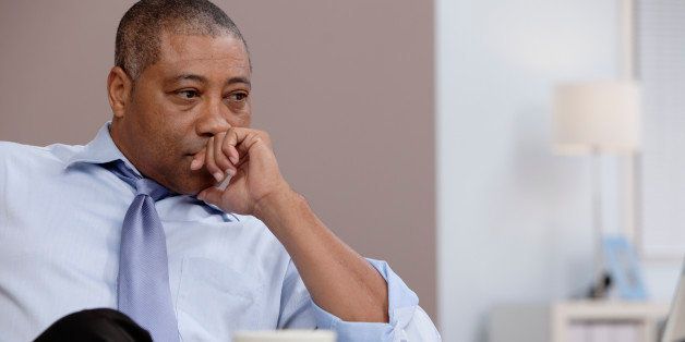 Black businessman thinking at desk in office