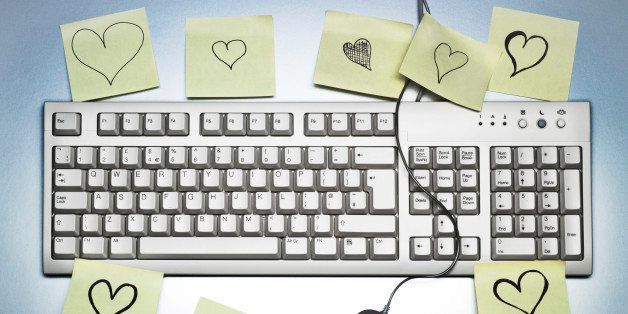 A computer keyboard covered in sticky memo notes notes with hearts drawn on them, a desk scene.