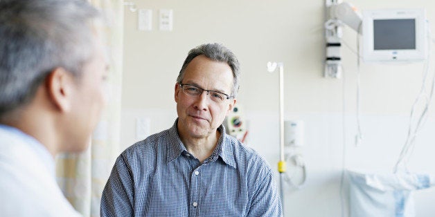 Doctor talking to mature male patient in hospital room