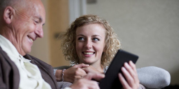 Senior man and smiling woman using digital tablet