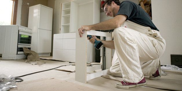 Man assembles kitchen units from packages. The packages come from furniture stores and must be assembled by the buyer. This concept contributes to cost savings for the buyer