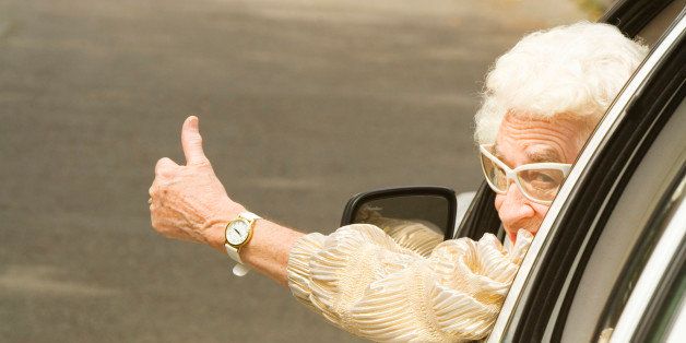 Senior woman giving thumbs up in car