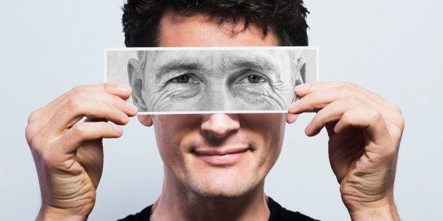 Young man holding picture of old eyes over his