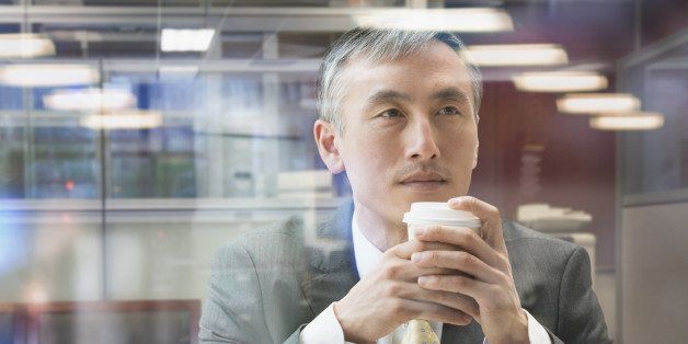 Chinese businessman drinking cup of coffee at window