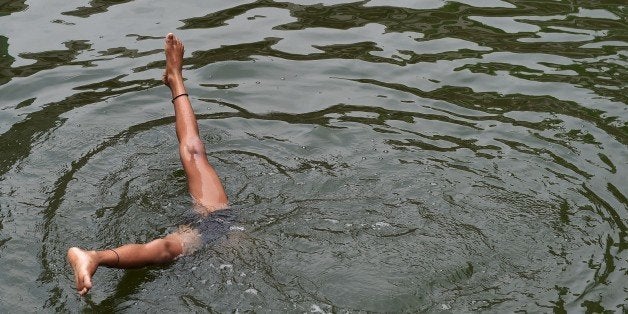 An Indian child dives into the water of a baoli, or a step-well, at the Nizamuddin Dargah in New Delhi on May 13, 2015. Tempe
