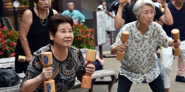 Elderly residents work out with wooden dumb-bells in the grounds of a temple in Tokyo on September 15, 2014 to celebrate Japa