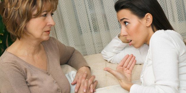 Mother and daughter sitting on the sofa and serious talking.