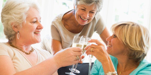 Three women in living room toasting champagne and smiling