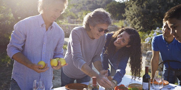 Multigenerational family preparing outdoor dining table in garden at sunset