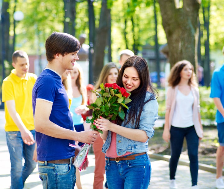 Couple of teenager on date outdoor. Group of people in background.