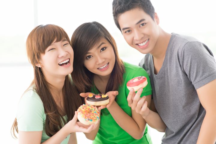 Three teenage friends offering little cakes