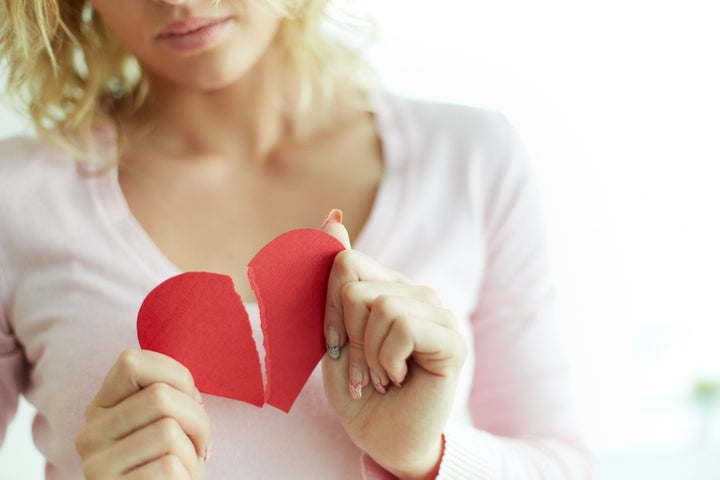 Close-up of female showing red broken paper heart