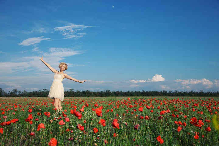 dancing girl in poppy field under blue sky