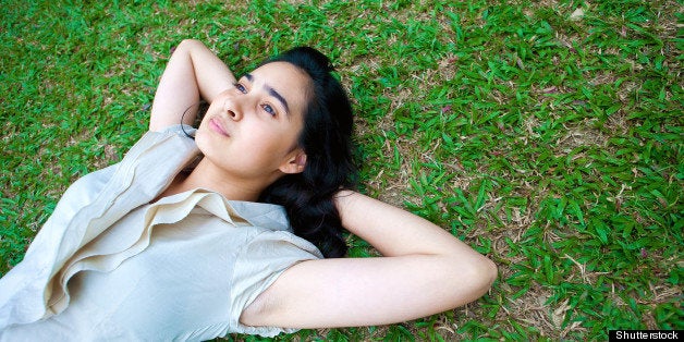 Beautiful young female laying on the grass, thinking