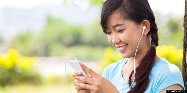 Young girl holding mp3 player in earphones on top of her head and listening music