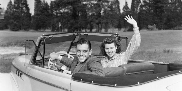 UNITED STATES - CIRCA 1940s: Teenage couple in convertible car smile and wave to viewer. (Photo by H. Armstrong Roberts/Retrofile/Getty Images)