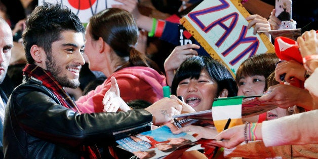 FILE - In this Sunday, Nov. 3, 2013 file photo, Zayn Malik of One Direction gives his autograph to Japanese fans during an ev