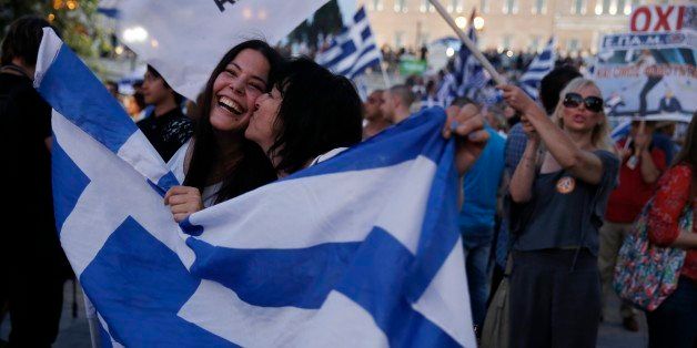 Supporters of the No vote react after the first results of the referendum at Syntagma square in Athens, Sunday, July 5, 2015. Greece faced an uncharted future as its interior ministry predicted Sunday that more than 60 percent of voters in a hastily called referendum had rejected creditors' demands for more austerity in exchange for rescue loans. (AP Photo/Petros Giannakouris)
