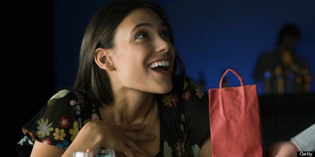 Woman being presented with gift, looking up in astonishment at giver