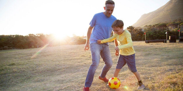 Caucasian father and son playing soccer in field