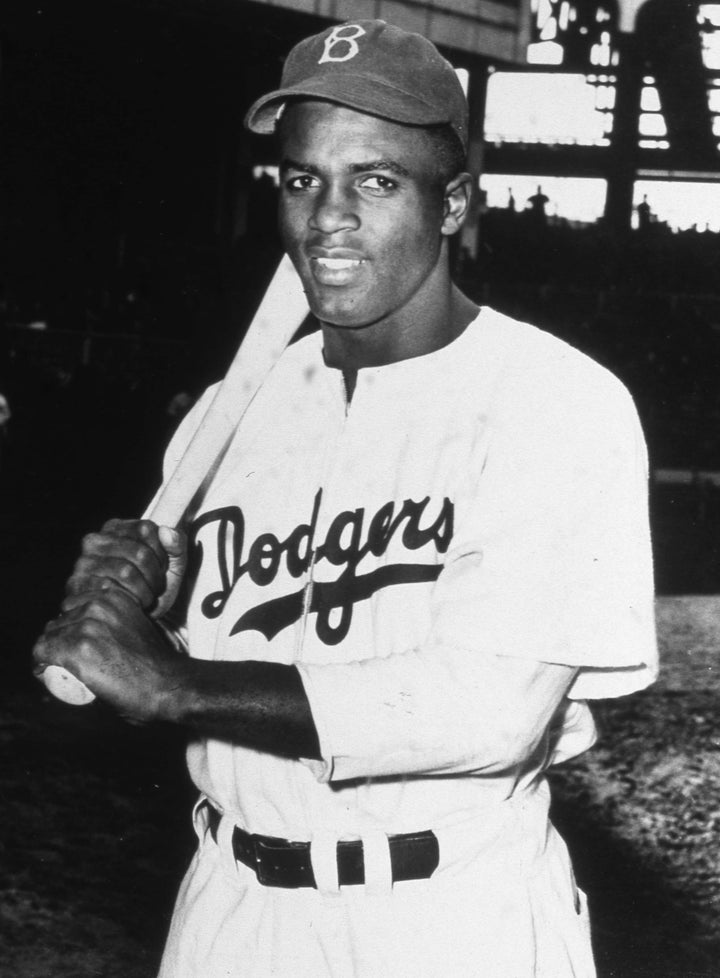 Brooklyn Dodger baseball star Jackie Robinson holding his young