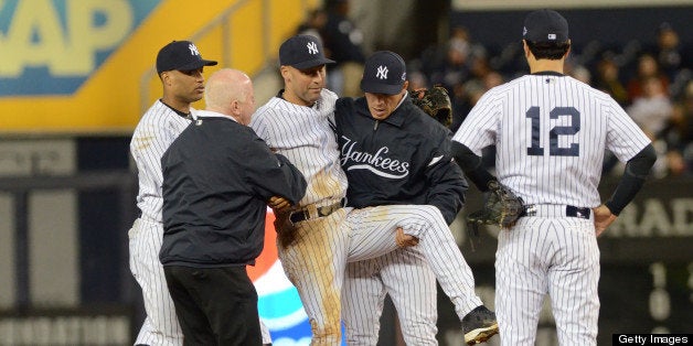 NEW YORK, NY - OCTOBER 13: Derek Jeter #2 of the New York Yankees is carried off the field by trainer Steve Donohue (L) and manager Joe Girardi #28 after Jeter fractured his left ankle in the top of the 12th inning against the Detroit Tigers during Game One of the American League Championship Series at Yankee Stadium on October 13, 2012 in New York City. The Tigers defeated the Yankees 6-4 in 12 innings. (Photo by Mark Cunningham/MLB Photos via Getty Images)