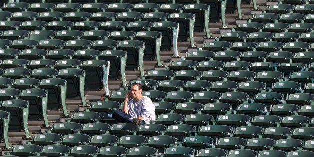 OAKLAND, CA - OCTOBER 21: A fan sits among empty seats while talking on a cell phone before the game between the Oakland Rai