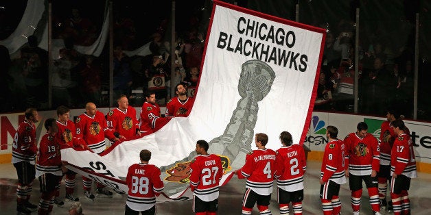 CHICAGO, IL - OCTOBER 01: Members of the Chicago Blackhawks watch as the 2013 Stanley Cup Championship banner is hung during