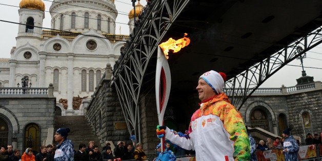 One of the participants of the Sochi 2014 Winter Olympic torch relay runs near the Christ the Saviour Cathedral in Moscow, on
