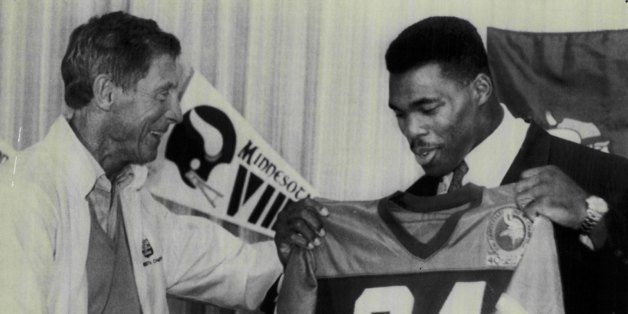 MINNEAPOLIS, MN - CIRCA 1989: Minnesota Vikings coach Jerry Burns greets Herschel Walker #34 of the Minnesota Vikings as Walker holds up his Vikings' jersey during a 1989 press conference after Walker was traded by the Dallas Cowboys to the Vikings in Minneapolis, Minnesota. Walker played for the Vikings form 1989-91. (Photo by Sporting News via Getty Images) 