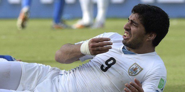 Uruguay forward Luis Suarez puts his hand to his mouth after clashing with Italy's defender Giorgio Chiellini during a Group D football match between Italy and Uruguay at the Dunas Arena in Natal during the 2014 FIFA World Cup on June 24, 2014. Uruguay won 1-0. AFP PHOTO / DANIEL GARCIA (Photo credit should read DANIEL GARCIA/AFP/Getty Images)