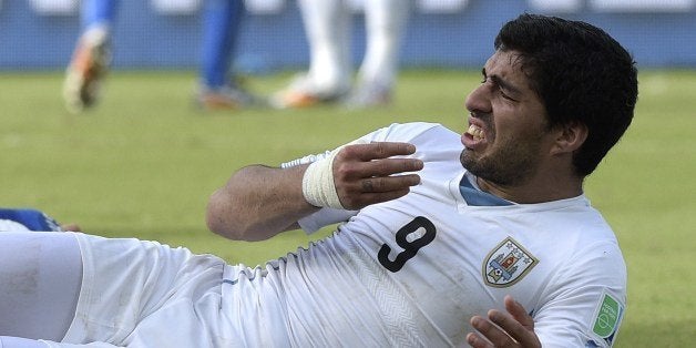 Uruguay forward Luis Suarez puts his hand to his mouth after clashing with Italy's defender Giorgio Chiellini during a Group D football match between Italy and Uruguay at the Dunas Arena in Natal during the 2014 FIFA World Cup on June 24, 2014. Uruguay won 1-0. AFP PHOTO / DANIEL GARCIA (Photo credit should read DANIEL GARCIA/AFP/Getty Images)